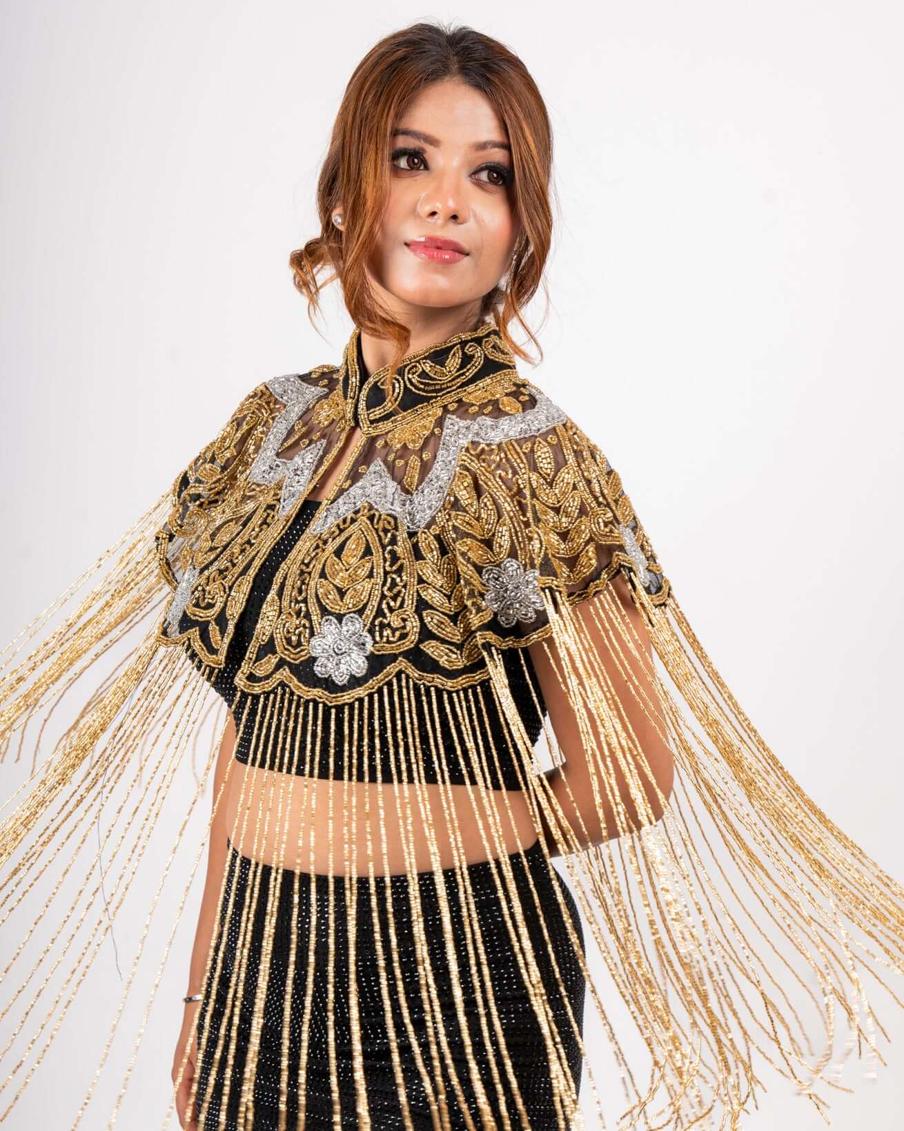 Intricately embroidered in gold and silver, this fringe cape adds a touch of opulence and drama to your evening ensemble.