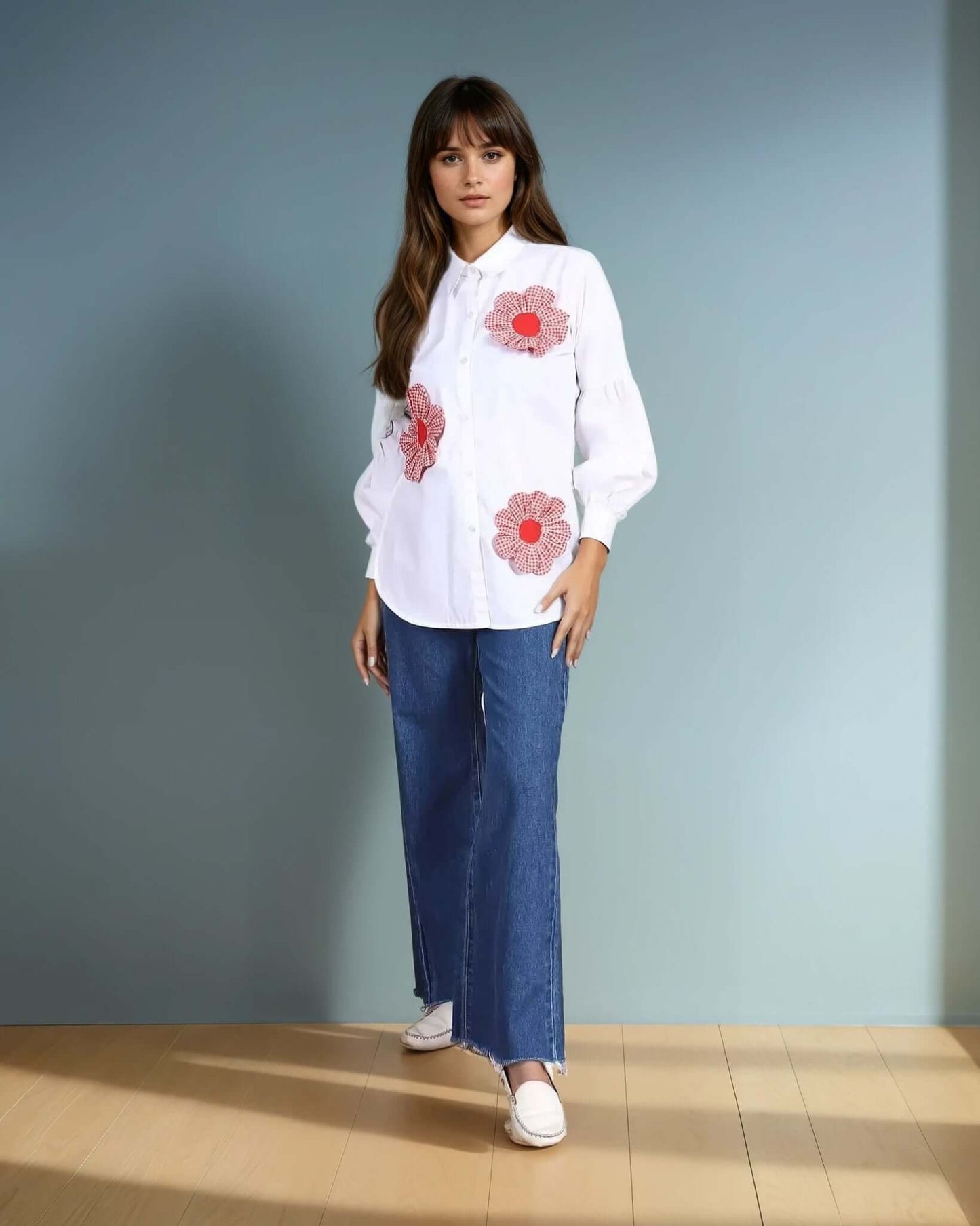 A model wearing a white oversized button-down shirt adorned with red gingham floral appliquΓ©s from House Of Majisha, paired with high-waisted wide-leg denim jeans and white loafers. The outfit blends casual elegance with a touch of statement detailing, perfect for chic everyday wear.
