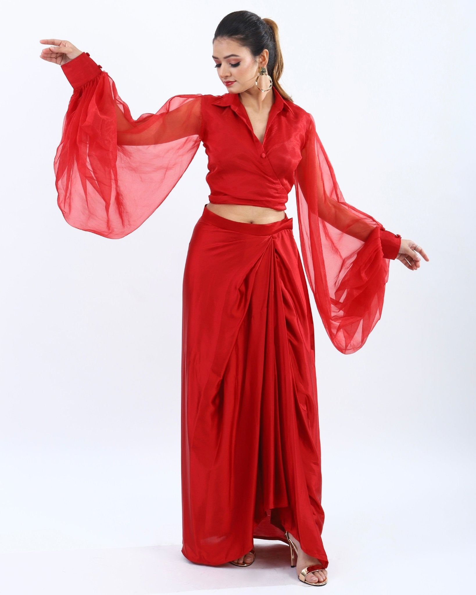 Bold red co-ord set for women featuring low-cut top with billowy sleeves and high-waisted skirt with slit for a playful yet elegant look.