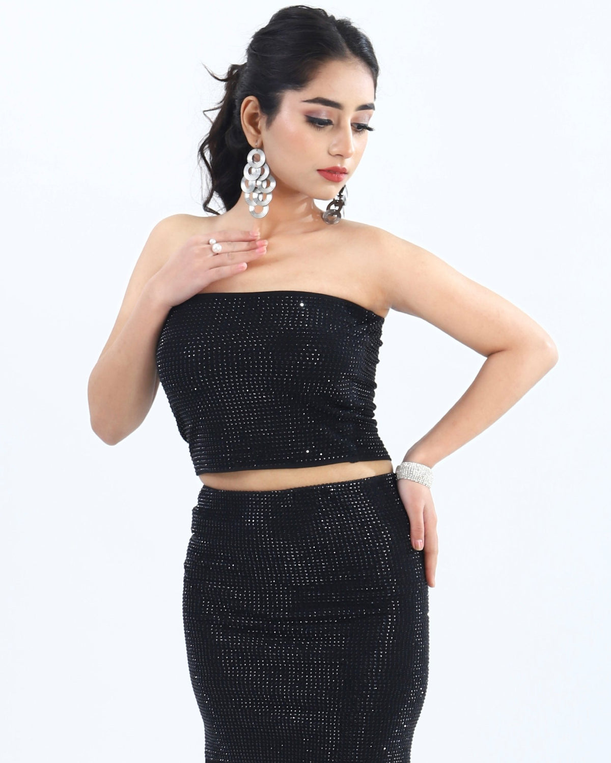 Woman in a black sequined strapless top and skirt set, posing against a simple background.