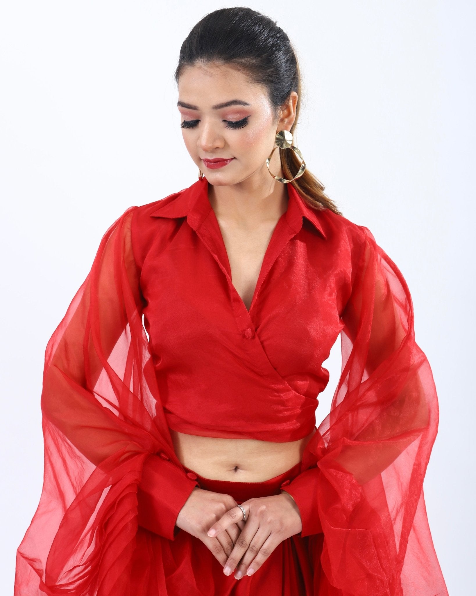 Bold red co-ord set with low-cut neckline, billowy sleeves, high-waisted skirt, and slit detail for a playful yet elegant look.