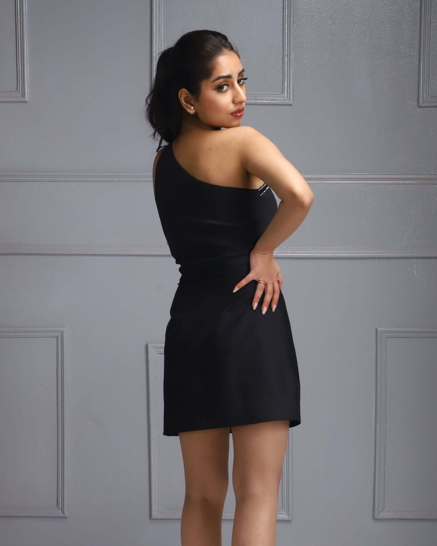 Little Black Dress a standout lady outfit ideas. Female Fashion Inspiration. Hand on Hip Styling Tips. Panelled Backdrop Photoshoot Techniques.