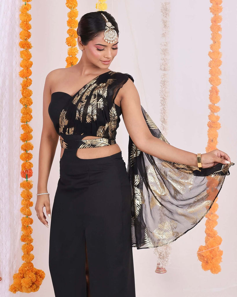 Black One-Shoulder Fusion Set: Elegant black one-shoulder fusion set with gold foil work, cut-out waist detailing, and high slit skirt for a modern and glamorous look.