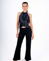 Woman wearing a chic black halter top with fringe details and backless design, perfect for parties and evening outings