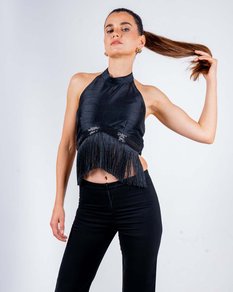 Woman wearing black halter top with fringe details and backless design, holding her ponytail, perfect for parties and nights out