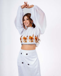 Woman wearing a white crop top with balloon sleeves and orange floral prints, paired with a matching pencil skirt.