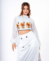 White crop top and skirt set with orange and brown floral prints, sheer balloon sleeves, high neckline, perfect for casual day wear.