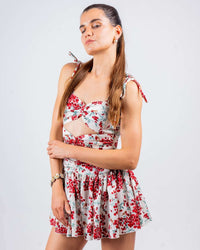 Woman wearing white and red floral cut-out skater dress with sweetheart neckline, perfect for beach wear, club wear, and parties.