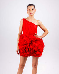 Woman wearing vibrant red one-shoulder ruffled doll dress made of organza with dramatic layers and a playful silhouette.