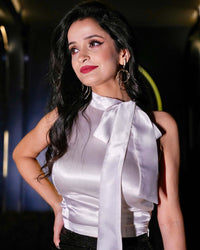 Close-up of a model wearing a white satin halter-neck top with a bow tie detail from House Of Majisha, styled elegantly for an evening event.