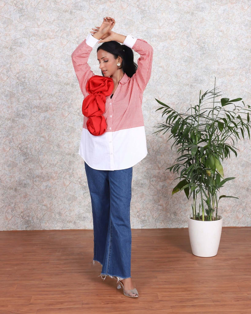 Woman wearing red stripe cotton shirt with ruffled sleeves, blue jeans, standing next to a potted plant, summer casual fashion.