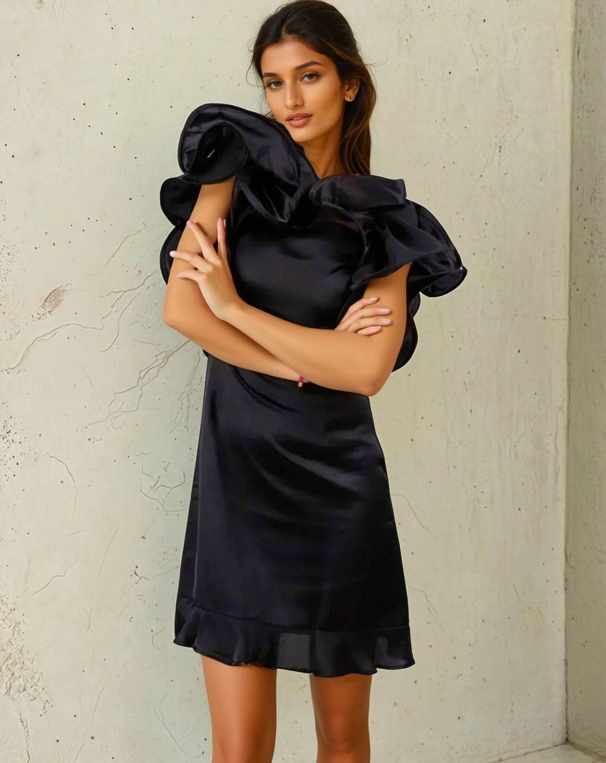 Woman wearing a ruffled black dress from House Of Majisha, crossing her arms and posing confidently against a neutral background.
