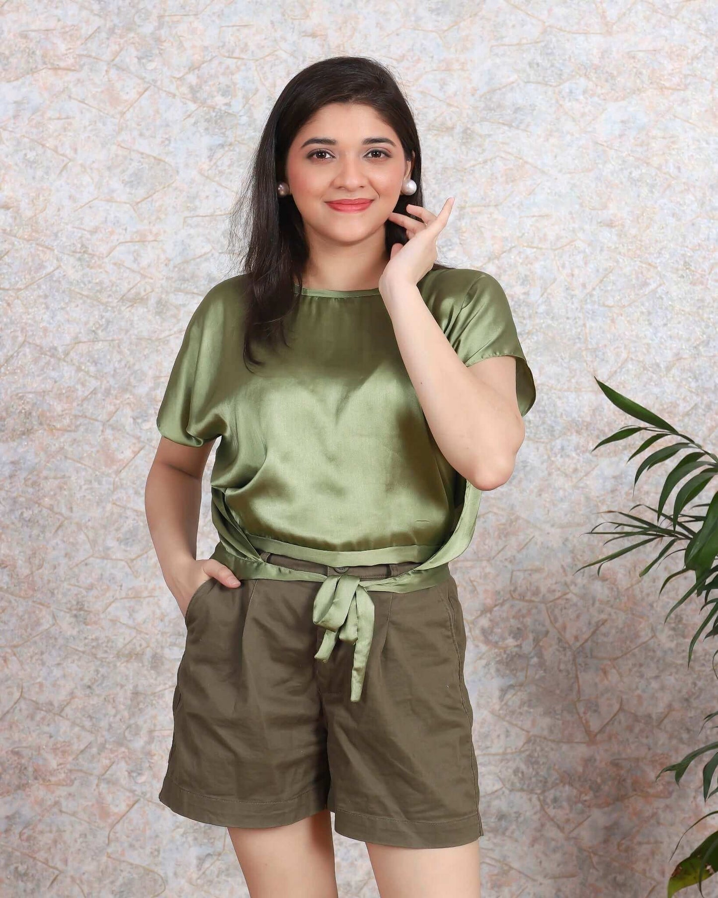 Woman wearing olive satin top with tie-front detail and brown shorts from House Of Majisha