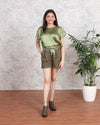 Woman wearing Olive Satin Top and shorts by House Of Majisha, standing next to a potted plant, perfect for party wear and western dresses.