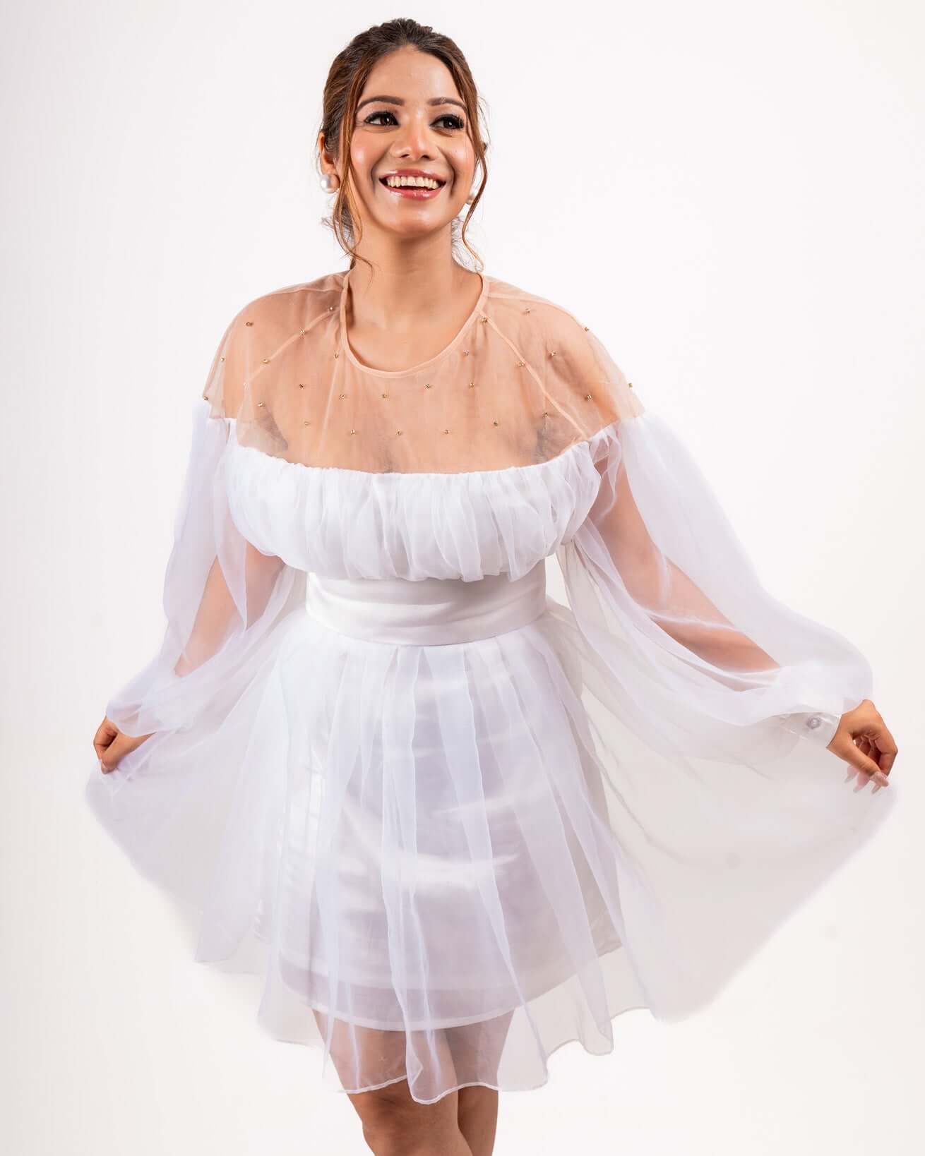 Woman wearing white organza balloon dress with net overlay, satin slip, and voluminous balloon sleeves, showcasing a chic and elegant style.