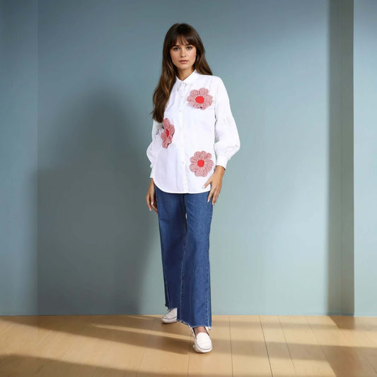 A model wearing a white oversized button-down shirt adorned with red gingham floral appliqués, paired with high-waisted wide-leg denim jeans and white loafers. The outfit blends casual elegance with a touch of statement detailing, perfect for chic everyday wear.