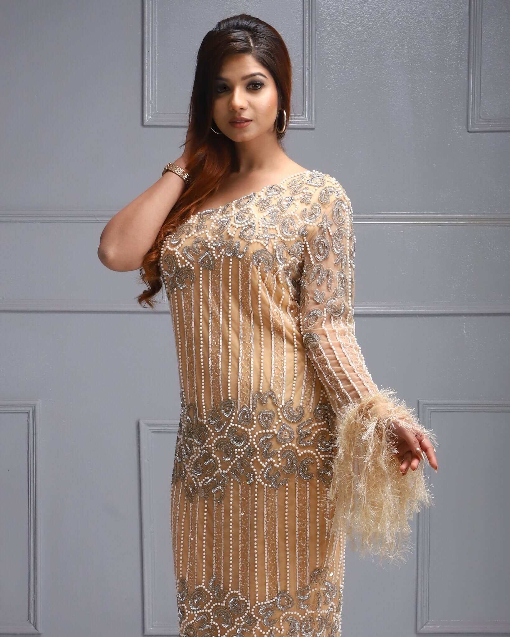 One shoulder beaded dress with feather sleeve, cutdana work, sequin detail, and sheer overlay.