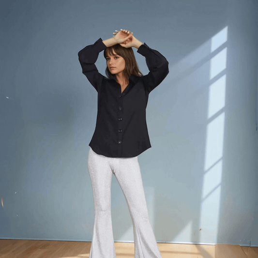 A model wearing a sleek black button-down shirt with puff sleeves, paired with shimmering silver sequined flared pants. The bold contrast of dark elegance and metallic shimmer creates a sophisticated yet modern evening look, perfect for party wear or stylish statement dressing.