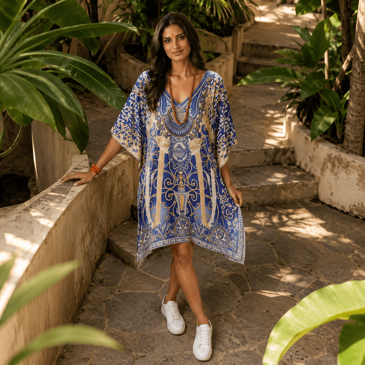 Woman in a house of majisha blue patterned kaftan dress standing in a garden setting