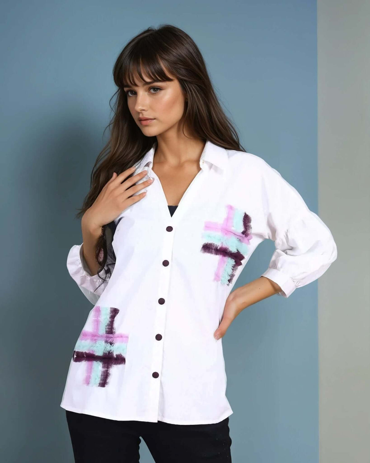 Model wearing a white oversized button-down shirt with artistic pink and purple brushstroke-style prints on the front pockets. The shirt features black buttons and three-quarter sleeves with buttoned cuffs, paired with slim black pants and pointed-toe heels for a modern, stylish look
