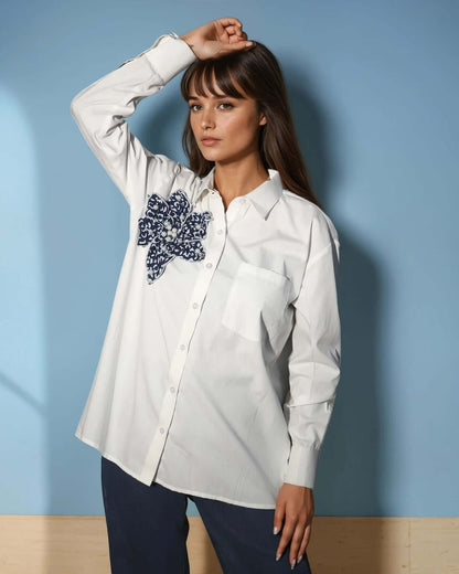 Model showcasing the Chic White Blossom Shirt in white, featuring a floral design, styled with dark trousers for a trendy casual look from House Of Majisha