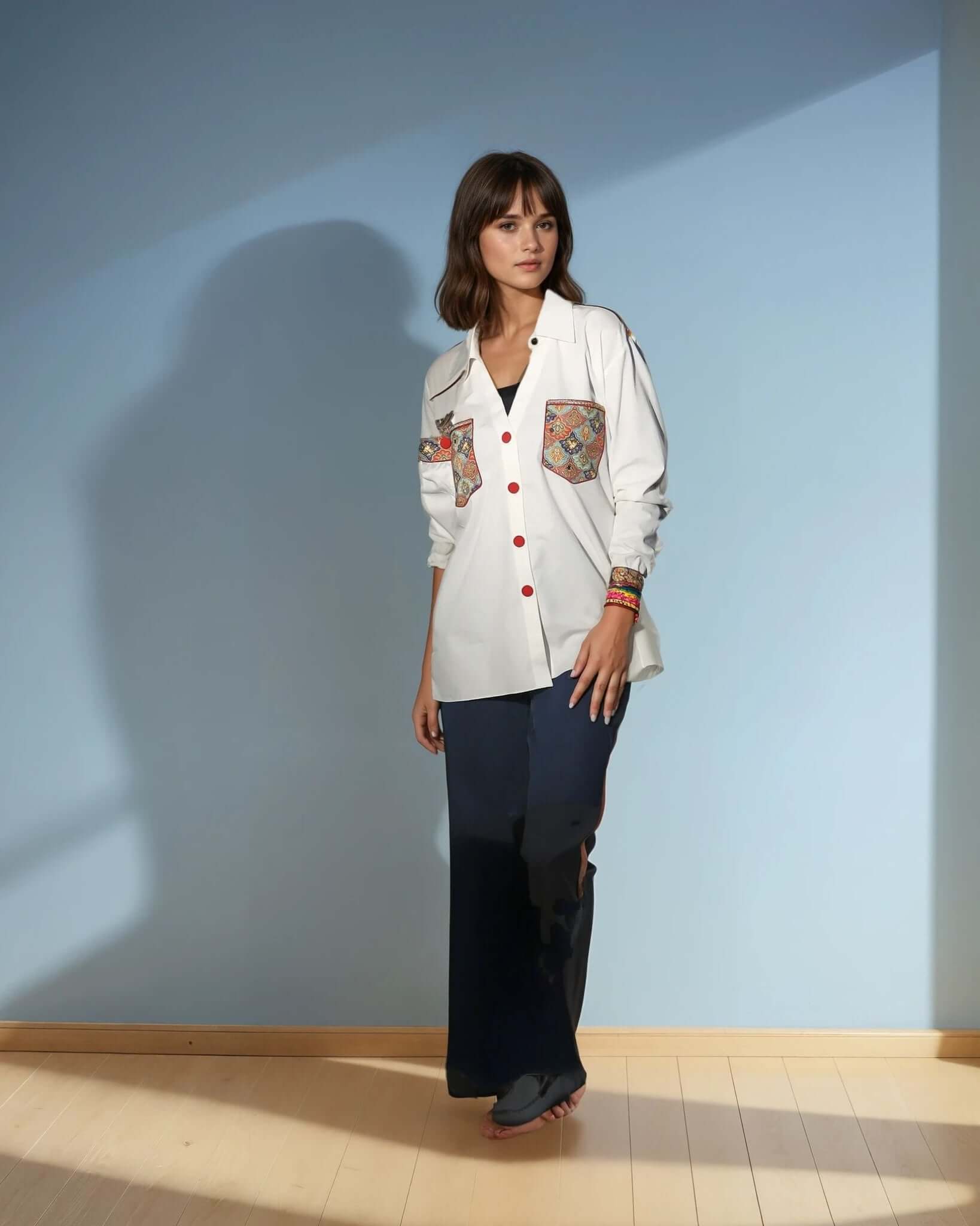Model wearing a white Chic Patchwork Shirt with colorful patchwork pockets, styled casually with dark pants, showcasing modern fashion from House of Majisha