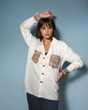Model wearing a white Chic Patchwork Shirt with colorful patchwork pockets, styled casually with dark pants, showcasing modern fashion from House of Majisha