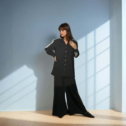 Model wearing a chic black shirt from House of Majisha, showcasing a trendy button-up design in a stylish indoor setting.