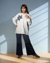 Model showcasing the Chic White Blossom Shirt in white, featuring a floral design, styled with dark trousers for a trendy casual look from House Of Majisha