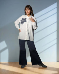 Model showcasing the Chic White Blossom Shirt in white, featuring a floral design, styled with dark trousers for a trendy casual look from House Of Majisha