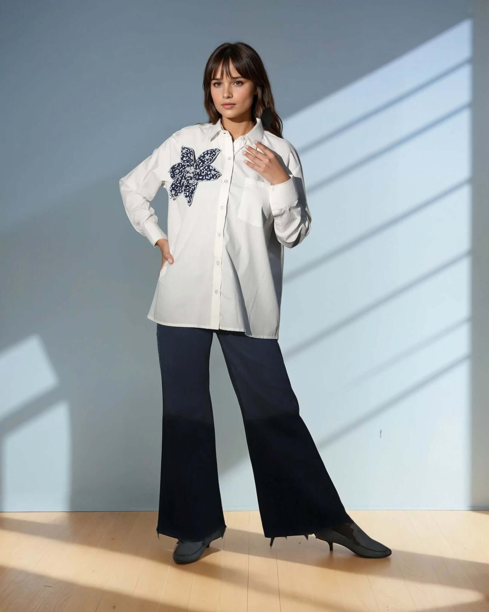 Model showcasing the Chic White Blossom Shirt in white, featuring a floral design, styled with dark trousers for a trendy casual look from House Of Majisha