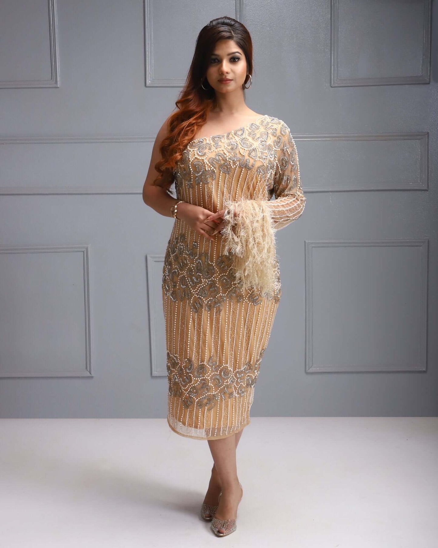 One shoulder beaded dress with feather sleeve, cutdana work, sequin detail, and sheer overlay.
