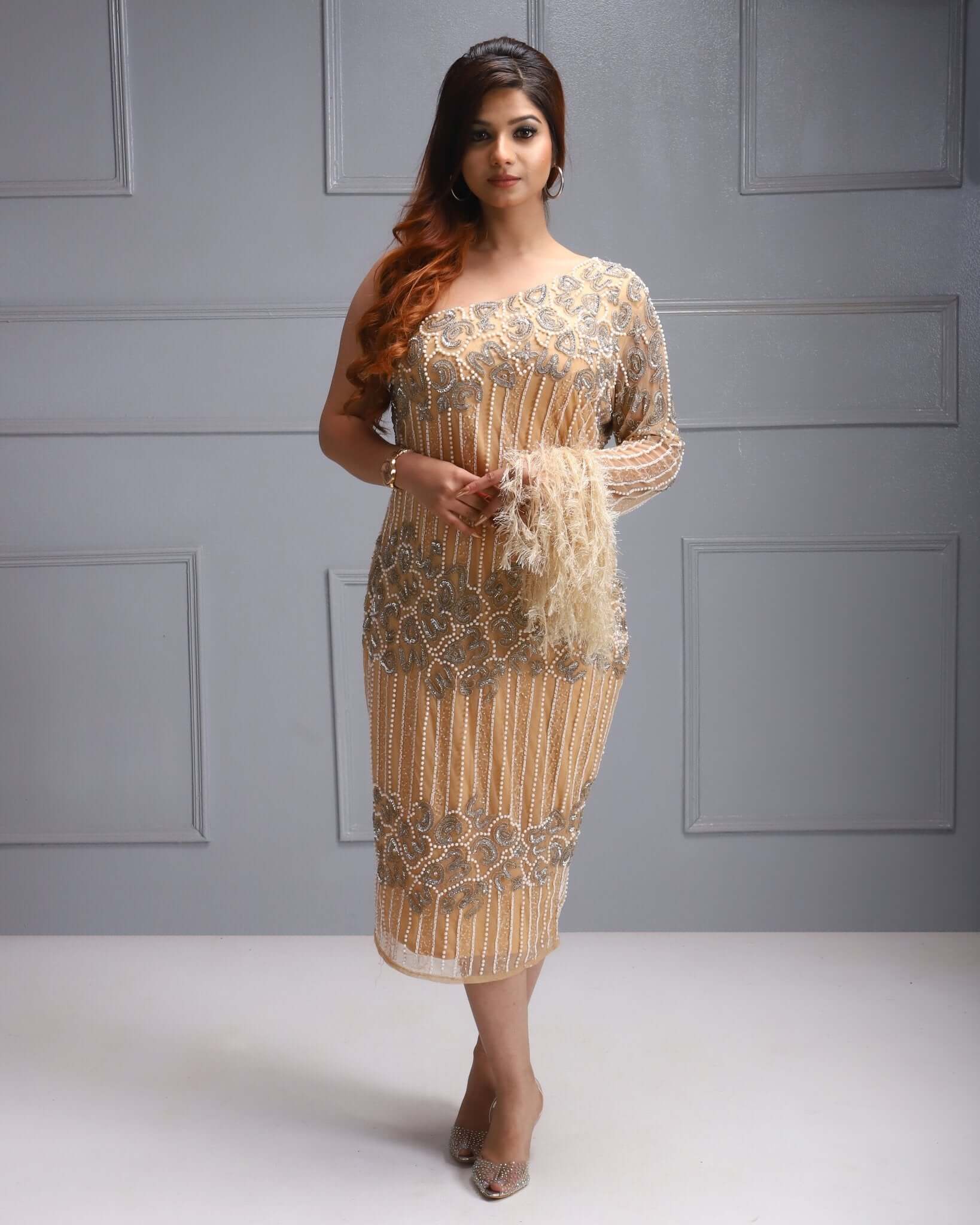One shoulder beaded dress with feather sleeve, cutdana work, sequin detail, and sheer overlay.