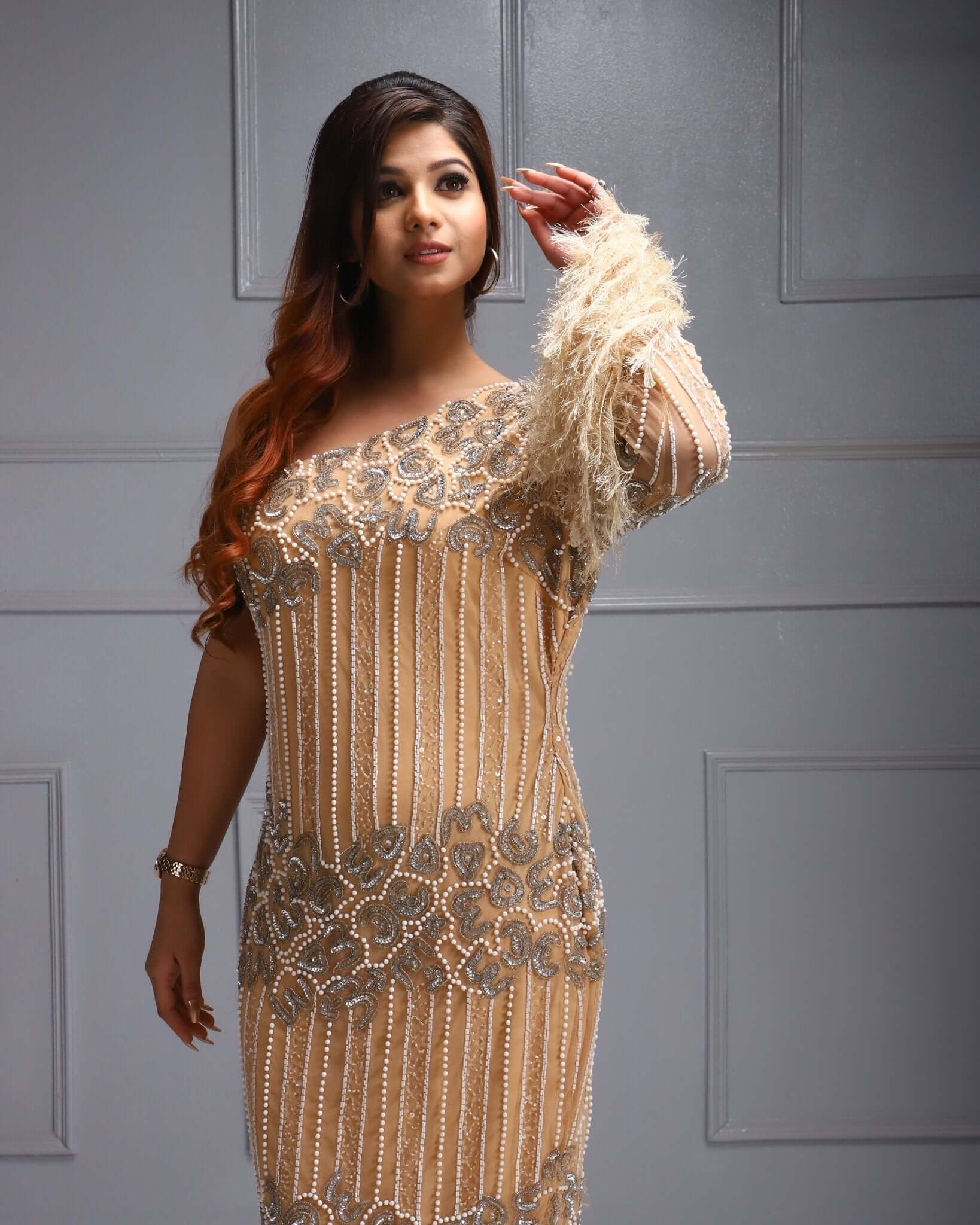 One shoulder beaded dress with feather sleeve, cutdana work, sequin detail, and sheer overlay.