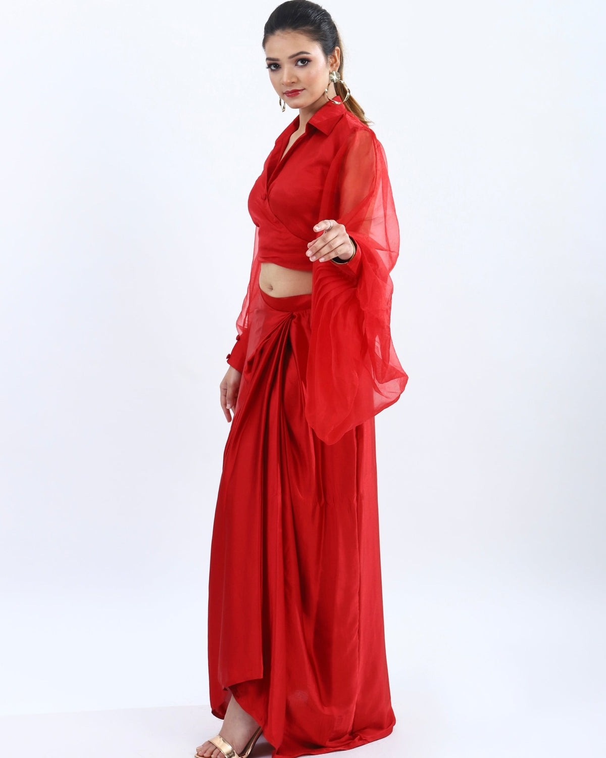 "Bold red co-ord set with low-cut neckline and billowy sleeves, paired with high-waisted skirt featuring a slit for added allure."