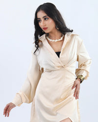 A poised woman in a cream satin wrap dress stands gracefully